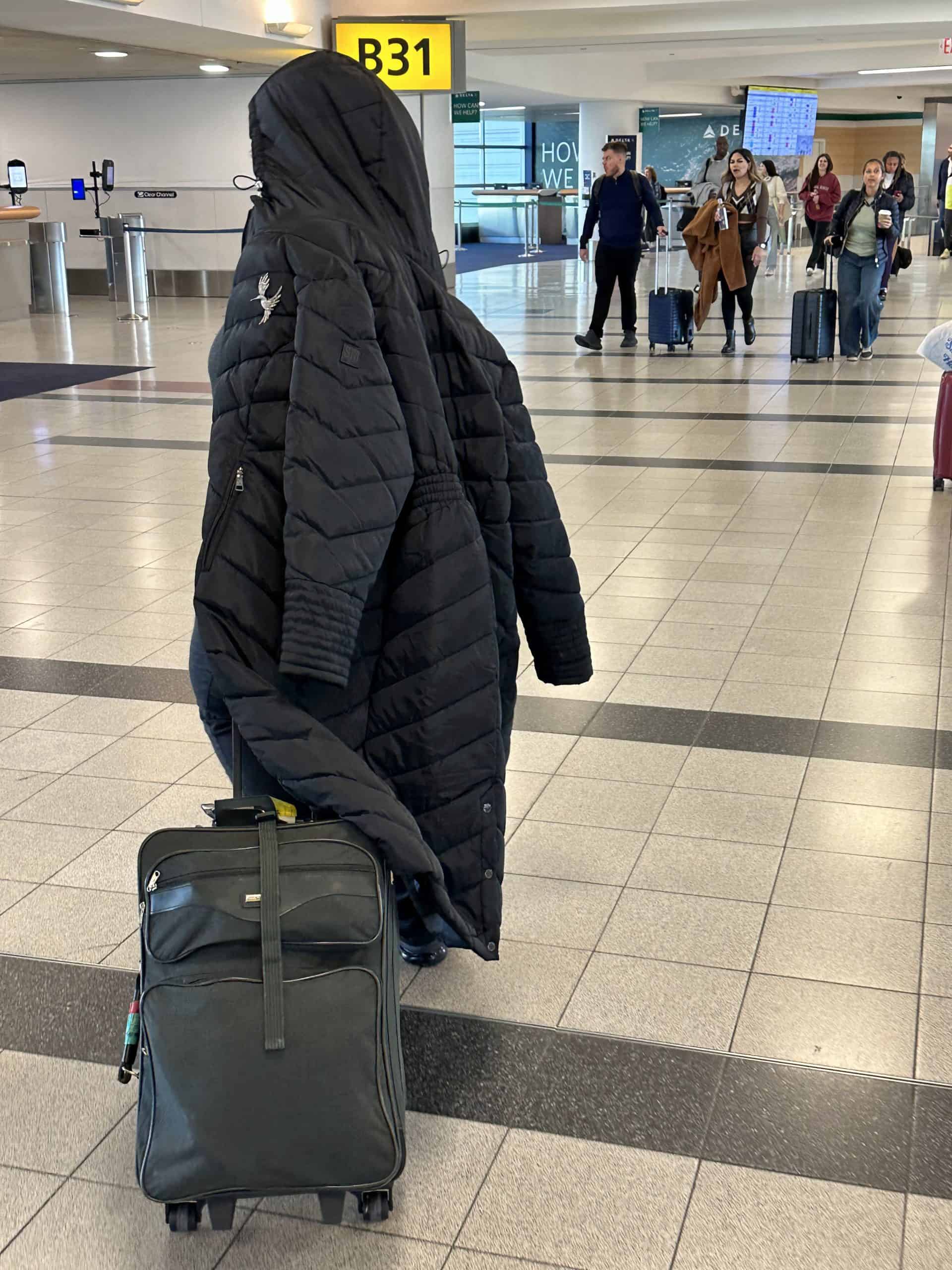 Lady dragging a too long, too heavy coat at JFK Airport