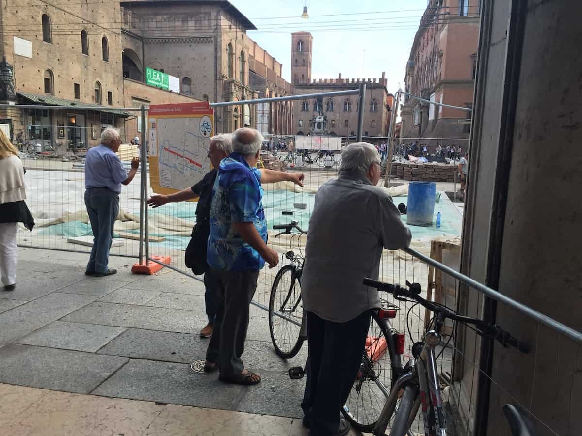 Men watching the repaving of Via Rizzoli in Bologna